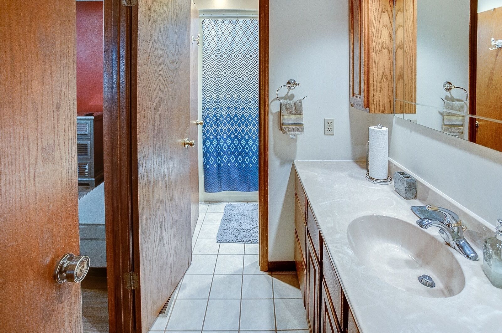A bathroom with a large sink, mirror, and wooden cabinets.