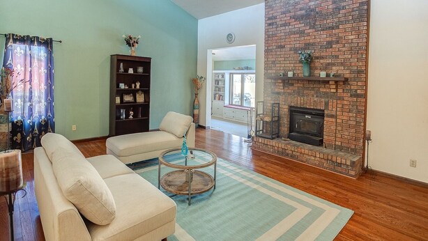 A living room with a sofa set, a coffee table, a fireplace, and a bookshelf. - Spacious Tranquility With Private Pool 4 Bedroom Home by RedAwning (Belleville)