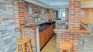 A kitchen with a stone backsplash, wooden bar stools, and a built-in oven. - Spacious Tranquility With Private Pool 4 Bedroom Home by RedAwning (Belleville)