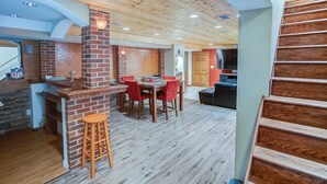 A spacious room with a brick fireplace, wooden flooring, a dining table with chairs, and a staircase. - Spacious Tranquility With Private Pool 4 Bedroom Home by RedAwning (Belleville)