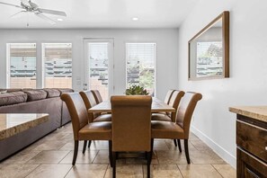 Un coin repas avec une table et des chaises, un canapé et un ventilateur de plafond.