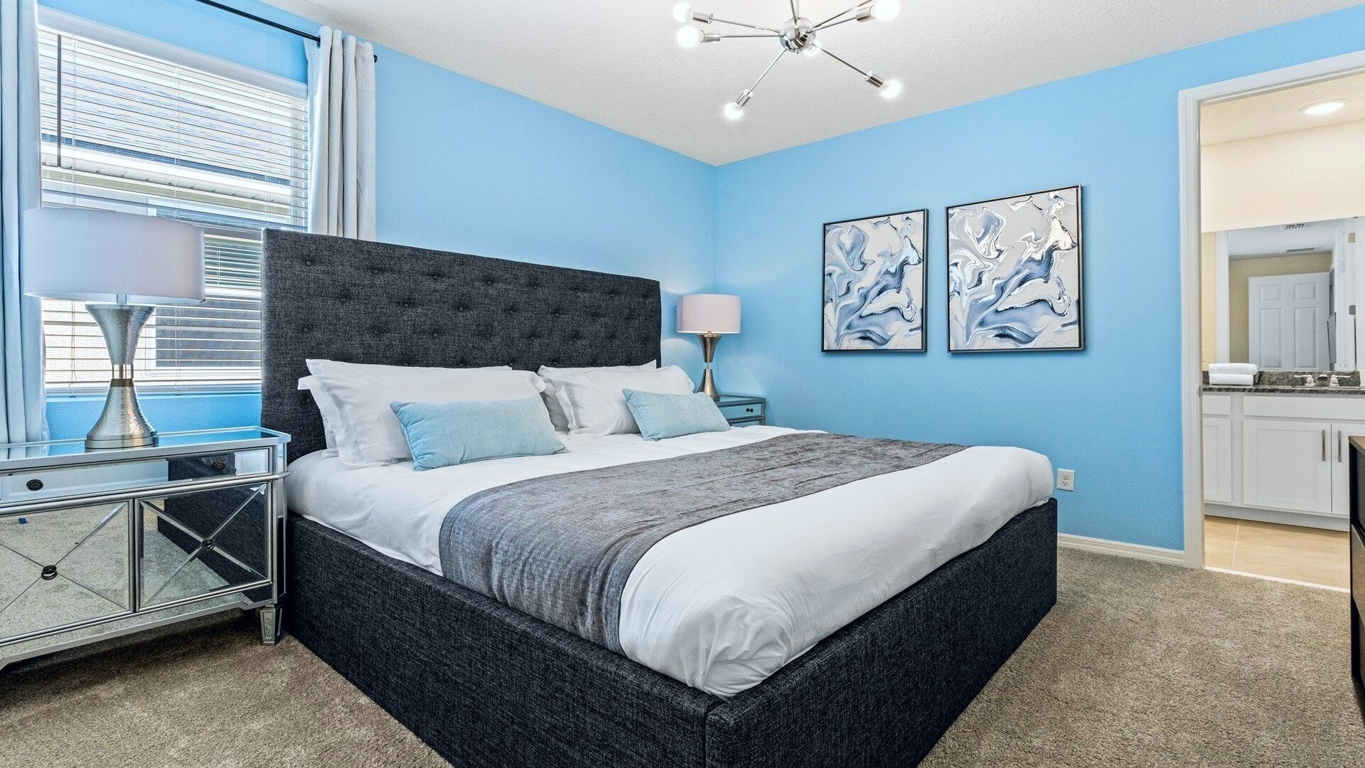 A bedroom with a bed, bedside tables, a lamp, and artwork on the wall.