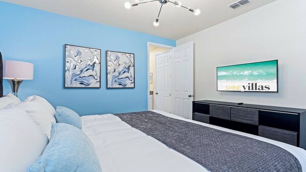 Un dormitorio moderno con una cama, un televisor y dos cuadros abstractos en la pared.