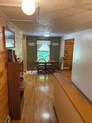 A wooden interior with a dining table and chairs, a wooden bench, and a window with curtains. - Hickey Creek Retreat Secluded Log Home - 7 miles from Pictured Rocks Lake shore (Shingleton)