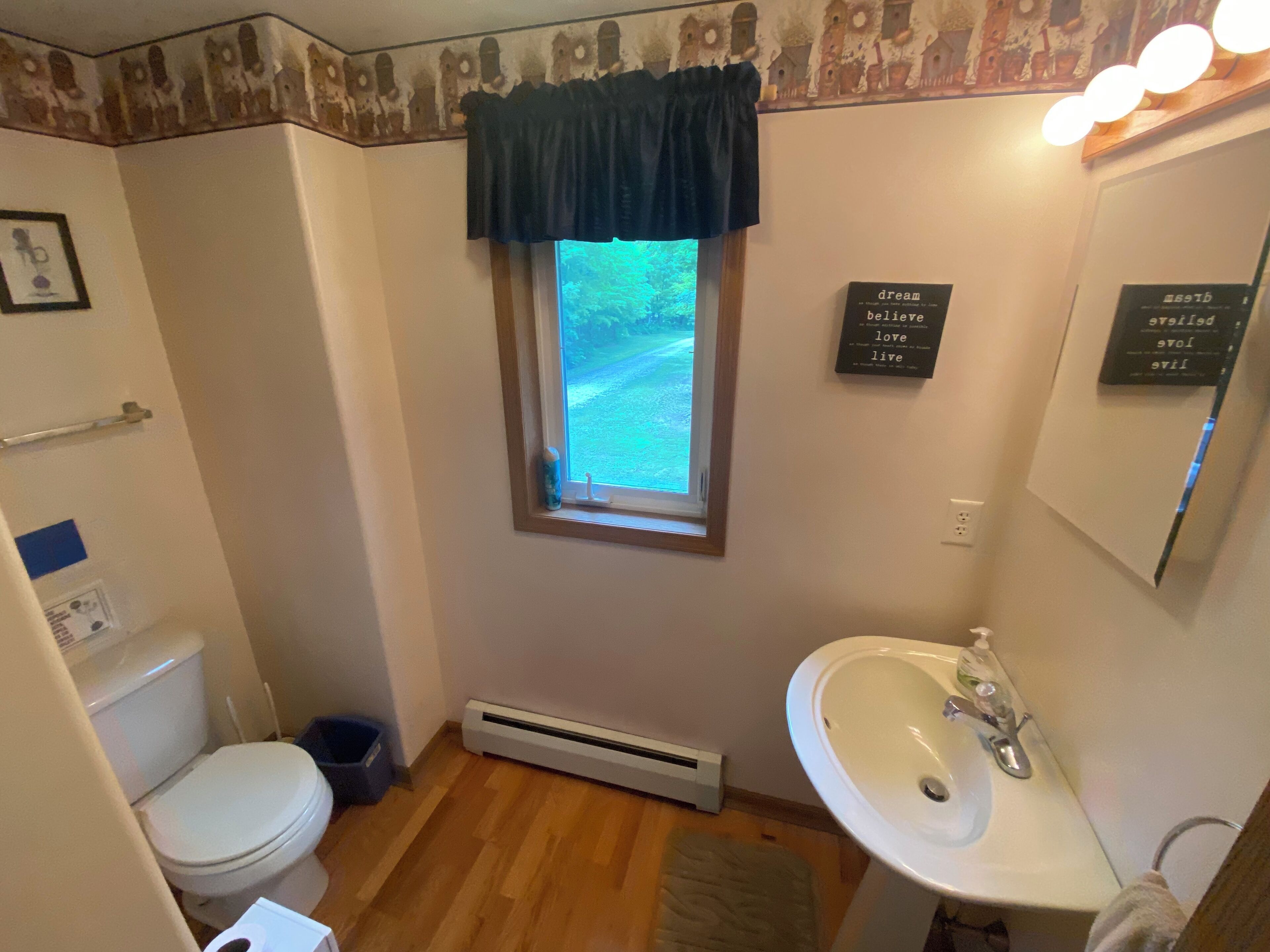 A bathroom with a toilet, sink, and window.