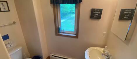 Un baño con inodoro, lavabo y ventana.
