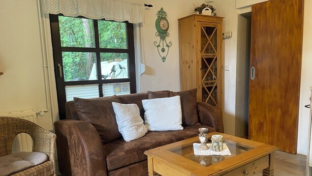 Un salon chaleureux avec un canapé marron, une table basse en verre, un fauteuil en osier et un meuble en bois.