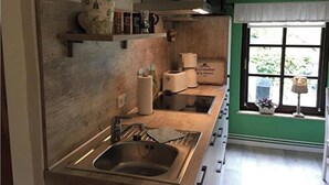 Une cuisine dotée d’un plan de travail en bois, d’un évier et d’une fenêtre donnant sur un paysage verdoyant.