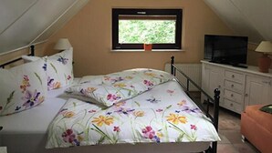 Une chambre à coucher avec un lit, une fenêtre, un téléviseur et une commode.