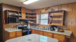 Una cocina con armarios de madera, encimera de granito, estufa y microondas.