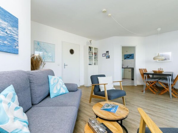 Un salon moderne avec un canapé gris, une table basse en bois et un coin repas comprenant une table et des chaises.