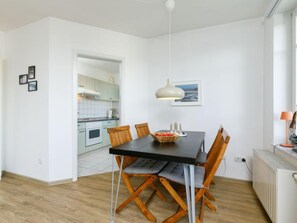 Une cuisine moderne avec des meubles blancs, une table à manger avec des chaises et un luminaire suspendu.