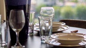 Spisebord dækket med tallerkener, glas og et stearinlys, med udsigt til bybilledet gennem et vindue.