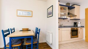 Une cuisine compacte avec un coin repas, comprenant une table avec des chaises, un radiateur et une cuisinière.