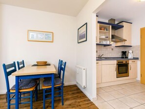 Cozinha compacta com área de refeições, com mesa e cadeiras, um radiador e um fogão.