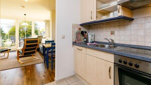 Une cuisine moderne avec des meubles en bois, un four encastré et une grande fenêtre donnant sur un jardin.