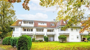 Une maison à deux étages, avec un toit recouvert de tuiles, de nombreuses fenêtres et un garage.