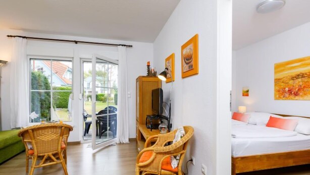 A room with a bed, two wicker chairs, a TV, and artwork on the wall. - Apartment Jacobs by Interhome (Zinnowitz)