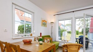 A dining area with a wooden table, chairs, a basket, and a bottle of champagne. - Apartment Jacobs by Interhome (Zinnowitz)