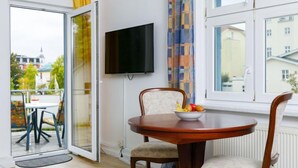 Une chambre moderne équipée d’une table à manger, de chaises, d’un téléviseur et offrant une vue sur l’extérieur.
