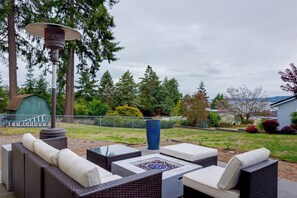 An outdoor patio area with wicker furniture, a fire pit, and a pergola.