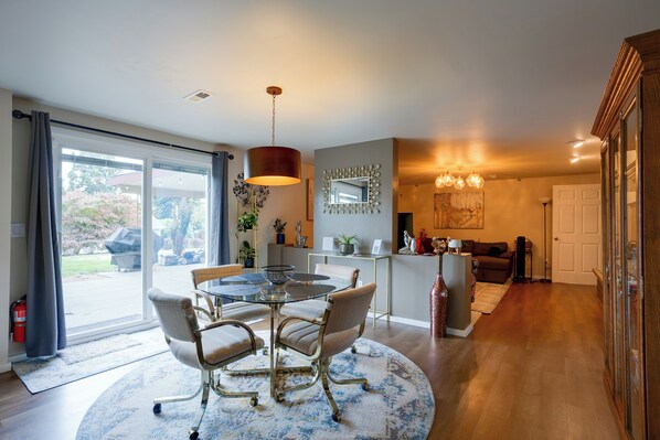 A modern kitchen with a dining area, large windows, and a view of the outdoors.