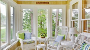 A sunlit room with wicker furniture, large windows, and a sign reading "Just Another day in Paradise". - Kennebunkport Getaway w/ Grill: Walk to Beach! (Kennebunkport)