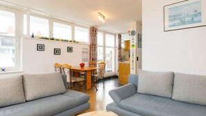 Un soggiorno moderno con due divani grigi, un tavolino in legno e un'area pranzo con tavolo e sedie in legno.