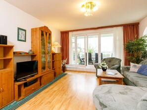 Un salon comprenant un meuble de rangement en bois pour les appareils multimédias, un canapé, une table basse et une plante en pot.