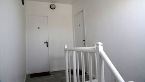 A hallway with a white door, a white railing, and a small rug on the floor. - JUPITER near gare station and market (Saint-Quentin)