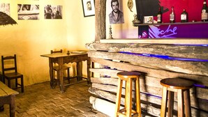 Eine rustikale Bar mit Holzhockern, einer Bar und einem Wandgemälde.