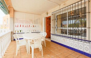 A dining area with a white table and chairs, a decorative wall with a perforated pattern, and a window with metal bars. - Pet friendly home in Los Alcazares (Los Alcazares)
