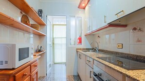 A narrow kitchen with white cabinets, a granite countertop, and a stainless steel sink. - Pet friendly home in Los Alcazares (Los Alcazares)