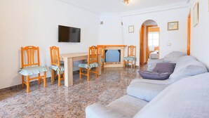 A living room with a sofa, chairs, a TV, a fireplace, and a bed in the background. - Pet friendly home in Los Alcazares (Los Alcazares)