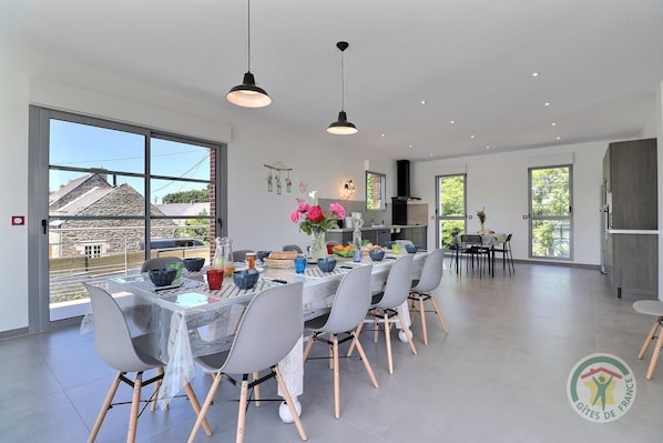 Un espace repas moderne avec une grande table dressée pour six personnes, entourée de chaises.
