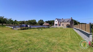 A large house with a stone exterior, a well-maintained lawn, and a solar panel array.