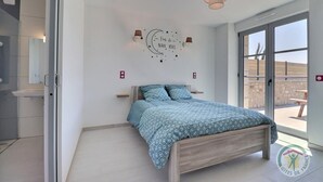 A bedroom with a bed, a wall clock, and a view of the outside.
