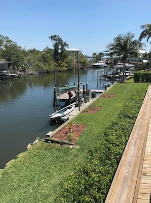 Uma marina com barcos atracados, um passeio gramado e um céu limpo.