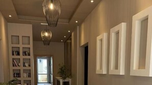 A modern hotel lobby with a long reception desk, a bookshelf, and a potted plant. - Mear Luxury Apartments and Studios (Kantanos-Selino)