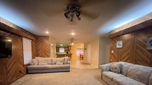 A living room with two sofas, a ceiling fan, and wooden paneling.