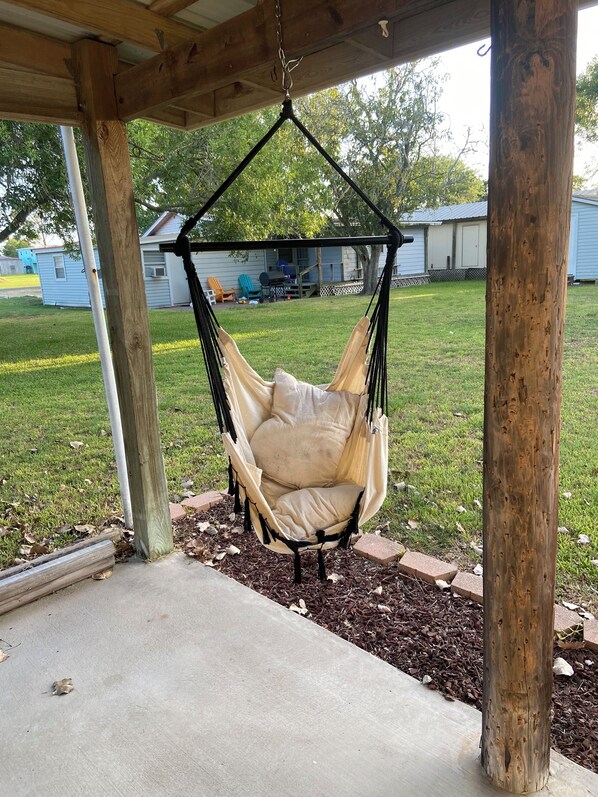 Una pérgola de madera con un sillón colgante color beige.