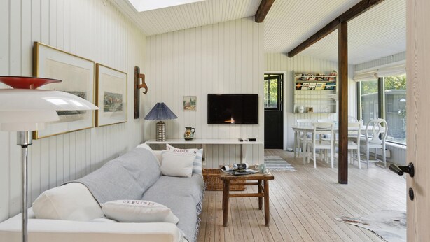 A cozy living room with a sofa, a TV, and a dining area with chairs and a table.