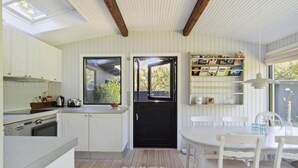 A compact kitchen with white cabinetry, a black door, and a window overlooking a garden.
