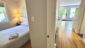 A bedroom with a bed, bedside lamp, and a view of the outside.
