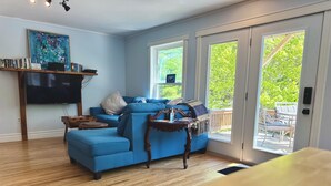 A living room with a blue sofa, a flat-screen TV, a wooden coffee table, and a bookshelf.