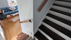 A staircase with dark steps and white risers, leading to a room with a blue sofa and a window.