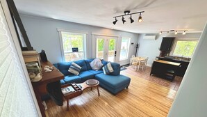 A living room with a blue sofa, wooden coffee table, and a dining area with a wooden table and chairs.