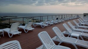 A deck with white lounge chairs facing a beach and ocean view. - Duplex in Siwar, 1 Bedroom, Next to Rimal, Wifi (Ghazir)