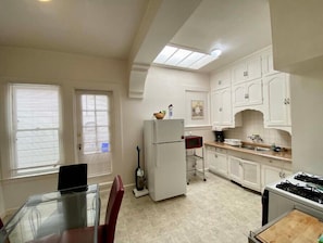 Compact kitchen with a refrigerator, microwave, and gas stove, featuring a window and ample storage.