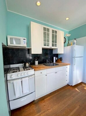 Een magnetron, kookgerei, borden en bestek, eettafels